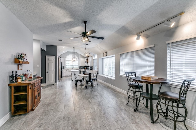 dining space with ceiling fan, lofted ceiling, and track lighting