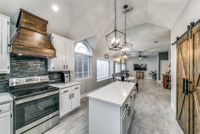 kitchen with stainless steel electric stove, a barn door, white cabinetry, and a center island