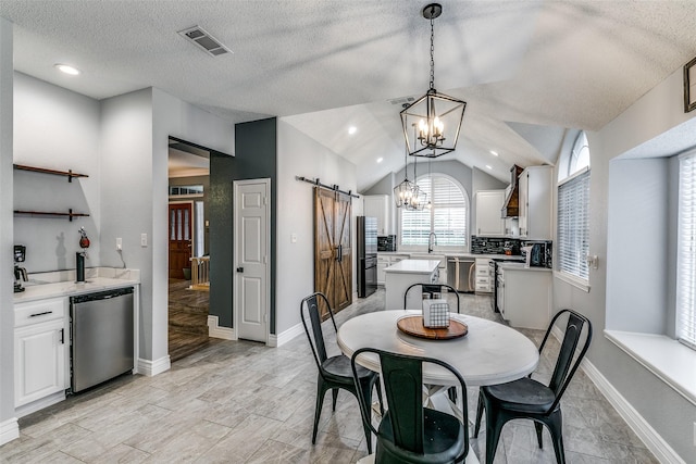 dining room with lofted ceiling, an inviting chandelier, sink, a barn door, and a textured ceiling