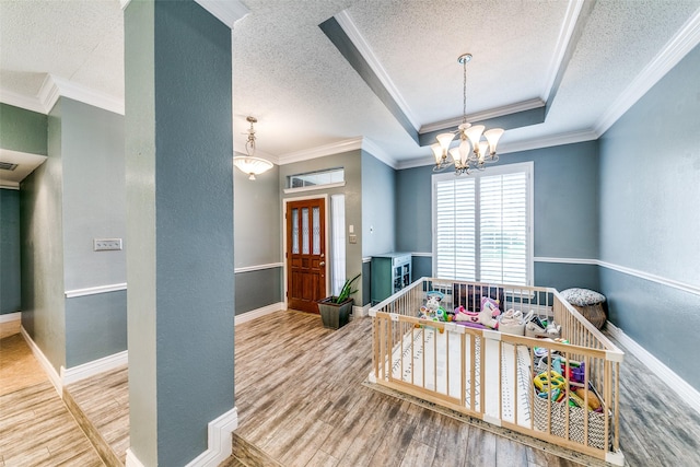 playroom with wood-type flooring, a raised ceiling, and ornamental molding