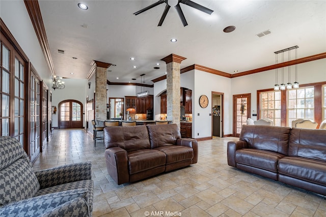 living room with ceiling fan with notable chandelier, ornate columns, crown molding, and a towering ceiling