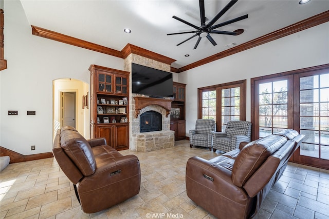 living room with ceiling fan, a stone fireplace, and ornamental molding