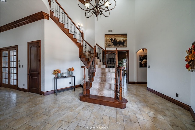 entryway featuring a towering ceiling, crown molding, and a notable chandelier