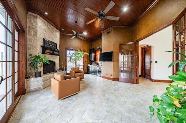 living room featuring ceiling fan, wood ceiling, a fireplace, and a towering ceiling