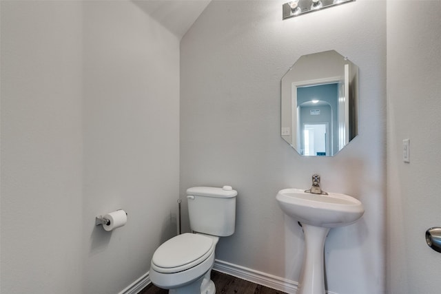 bathroom with wood-type flooring, lofted ceiling, and toilet