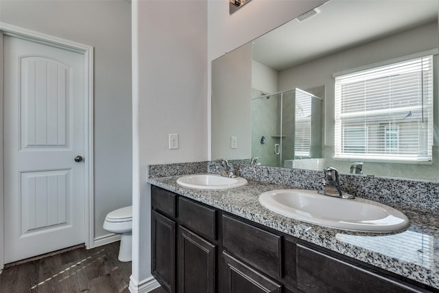 bathroom with hardwood / wood-style floors, vanity, toilet, and a shower with shower door