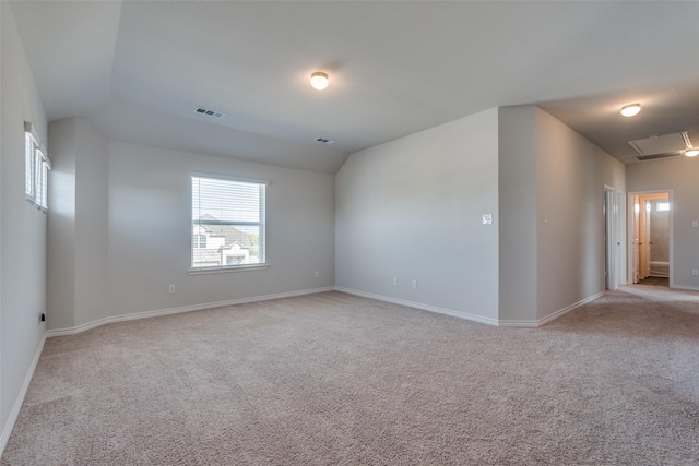 carpeted spare room with vaulted ceiling