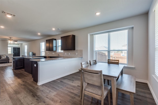 kitchen featuring tasteful backsplash, kitchen peninsula, light stone countertops, and dark hardwood / wood-style flooring