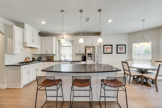 kitchen with white cabinets, a kitchen island, pendant lighting, and appliances with stainless steel finishes