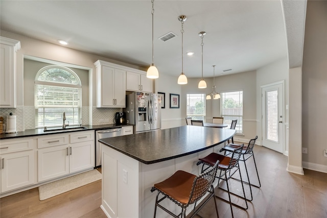 kitchen with decorative backsplash, stainless steel appliances, sink, a center island, and white cabinetry