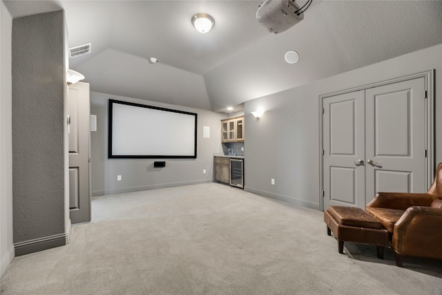 carpeted cinema featuring wine cooler, bar, and lofted ceiling