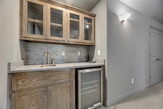 bar with light stone counters, sink, backsplash, and beverage cooler