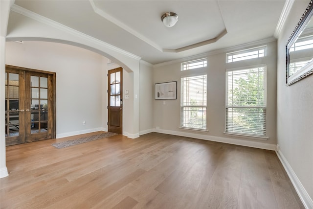 unfurnished room featuring french doors, light hardwood / wood-style flooring, a raised ceiling, and ornamental molding