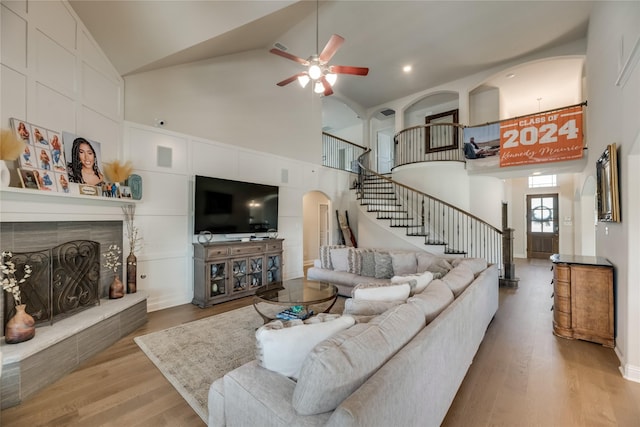 living room featuring a fireplace, wood-type flooring, high vaulted ceiling, and ceiling fan