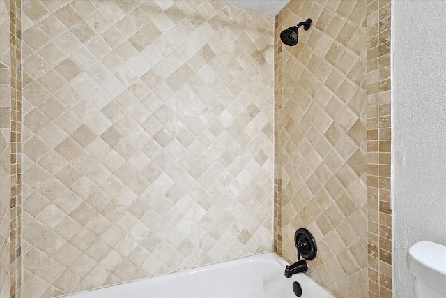 bathroom featuring tiled shower / bath combo and toilet