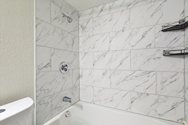 bathroom featuring tiled shower / bath combo and toilet