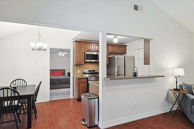 kitchen featuring decorative backsplash, dark stone countertops, lofted ceiling, and stainless steel appliances