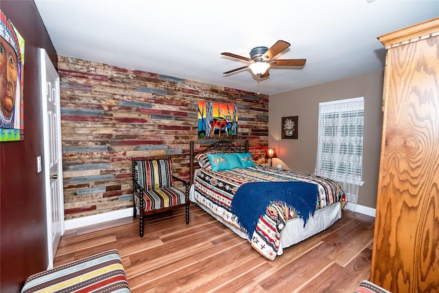 bedroom featuring hardwood / wood-style floors, ceiling fan, and wooden walls