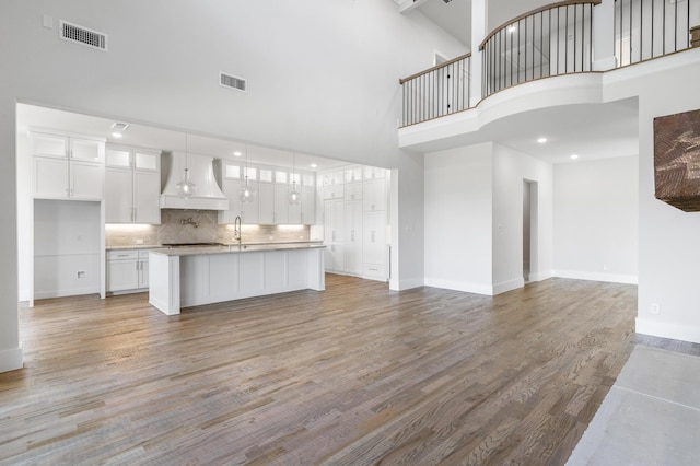 unfurnished living room with light wood-type flooring and a towering ceiling