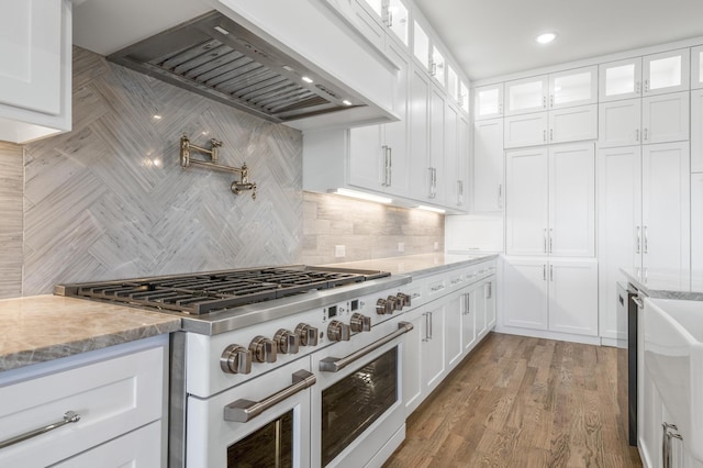 kitchen featuring white cabinetry, tasteful backsplash, light hardwood / wood-style floors, high end stainless steel range, and custom range hood