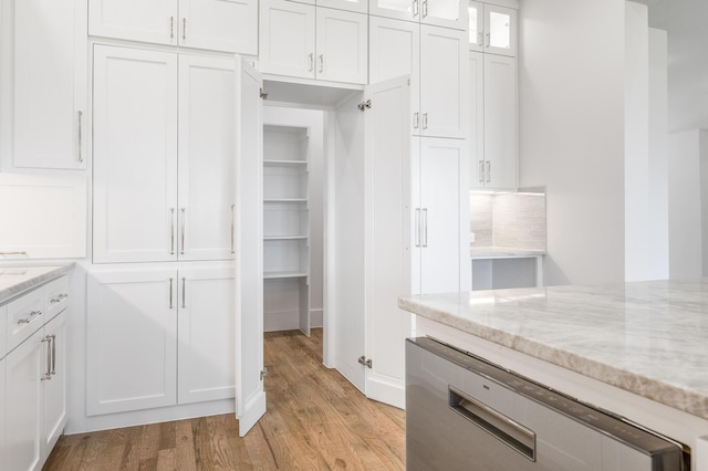 kitchen featuring light stone countertops, white cabinets, and light wood-type flooring