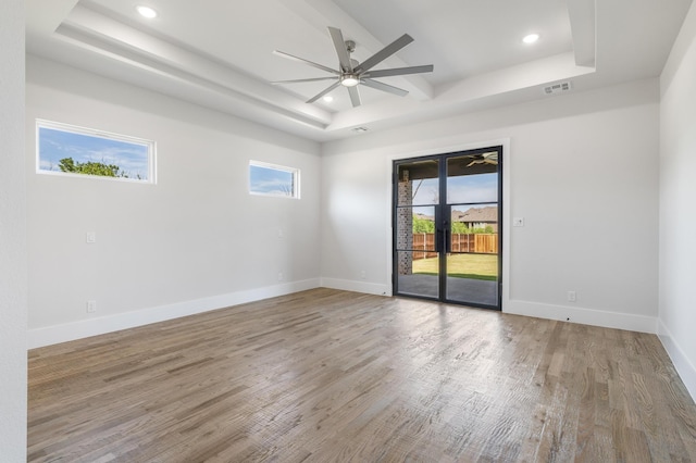 empty room featuring hardwood / wood-style floors, plenty of natural light, french doors, and a tray ceiling