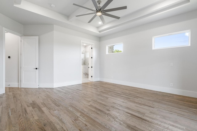 spare room with light wood-type flooring, a raised ceiling, and ceiling fan