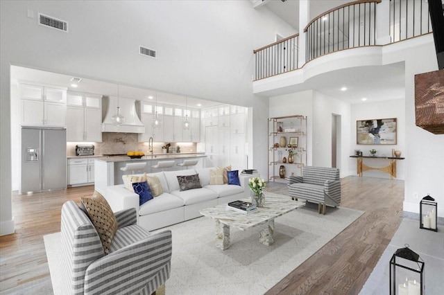 living room featuring a towering ceiling and light hardwood / wood-style flooring