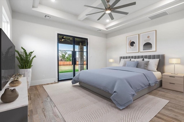 bedroom with hardwood / wood-style flooring, ceiling fan, a raised ceiling, and access to exterior