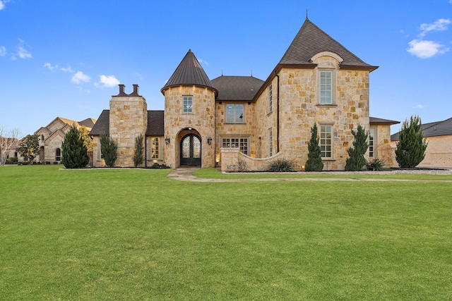 french country inspired facade featuring a front yard and french doors