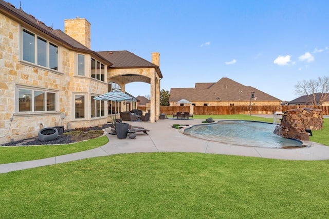 view of pool with a patio area, pool water feature, and a yard