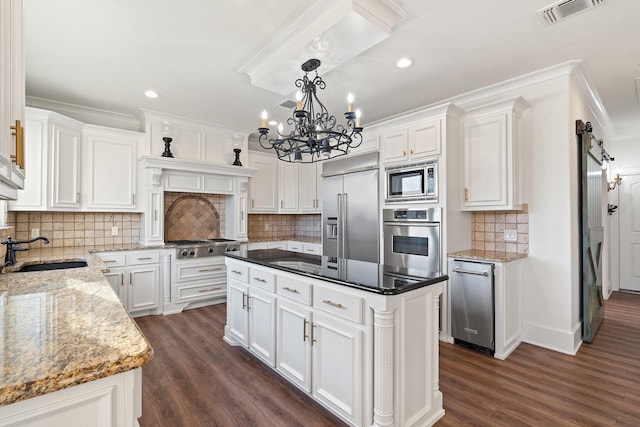 kitchen with built in appliances, white cabinetry, sink, and a barn door