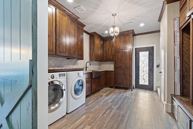 washroom with cabinets, crown molding, a chandelier, washer and dryer, and hardwood / wood-style flooring