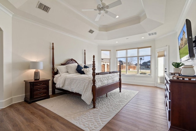 bedroom with a raised ceiling, ceiling fan, wood-type flooring, and ornamental molding