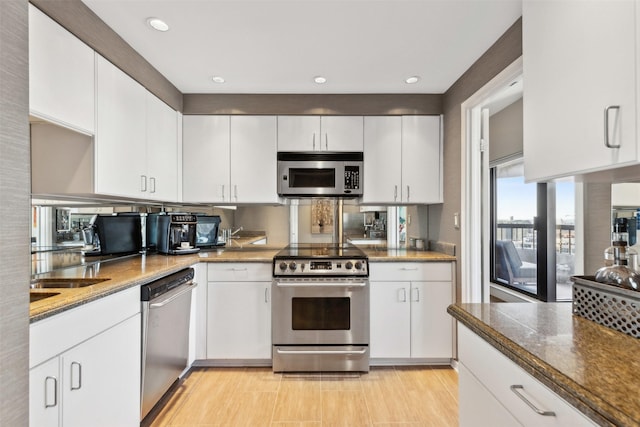 kitchen with appliances with stainless steel finishes, white cabinetry, and dark stone counters