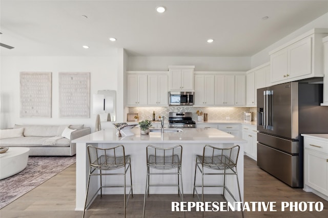 kitchen featuring an island with sink, stainless steel appliances, and white cabinetry