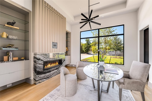 living area with built in shelves, plenty of natural light, a high end fireplace, and wood-type flooring