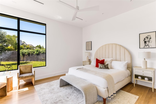 bedroom featuring ceiling fan, multiple windows, and light hardwood / wood-style flooring