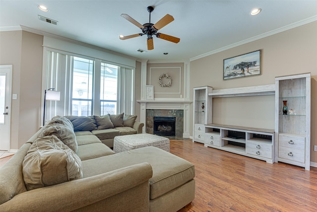 living room with a fireplace, hardwood / wood-style flooring, ceiling fan, and ornamental molding