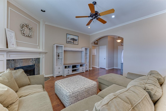 living room featuring a fireplace, dark hardwood / wood-style floors, ceiling fan, and ornamental molding