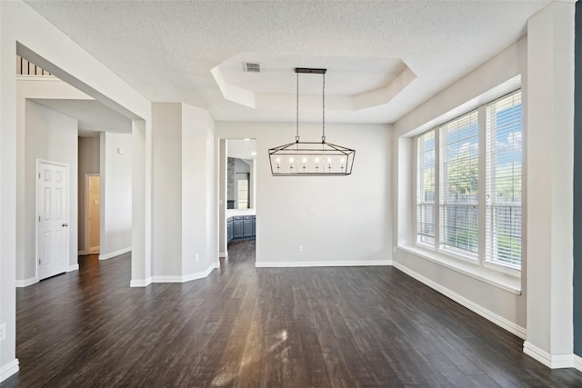 unfurnished dining area featuring a raised ceiling, dark wood-type flooring, and a textured ceiling