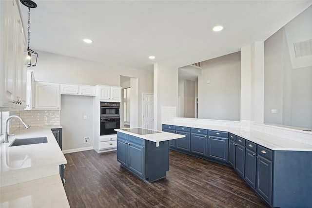 kitchen featuring blue cabinetry, sink, hanging light fixtures, backsplash, and white cabinets