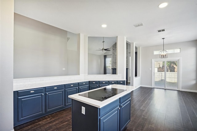 kitchen featuring blue cabinets, pendant lighting, black electric cooktop, a kitchen island, and ceiling fan with notable chandelier