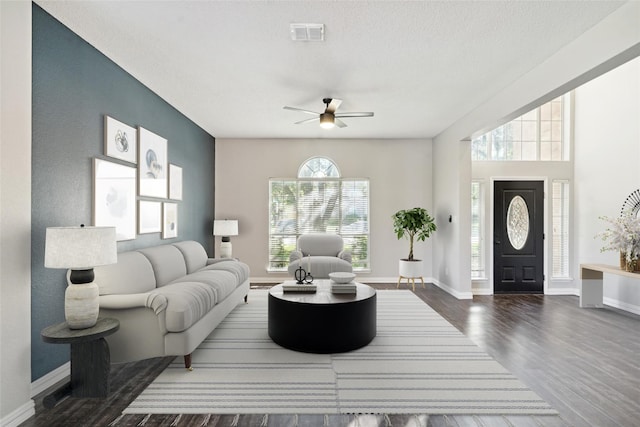 living room with a textured ceiling, dark hardwood / wood-style flooring, and ceiling fan