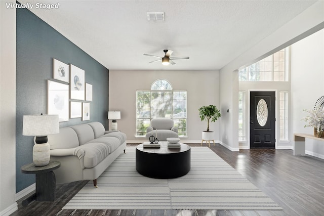 living room featuring ceiling fan, dark hardwood / wood-style flooring, and a textured ceiling