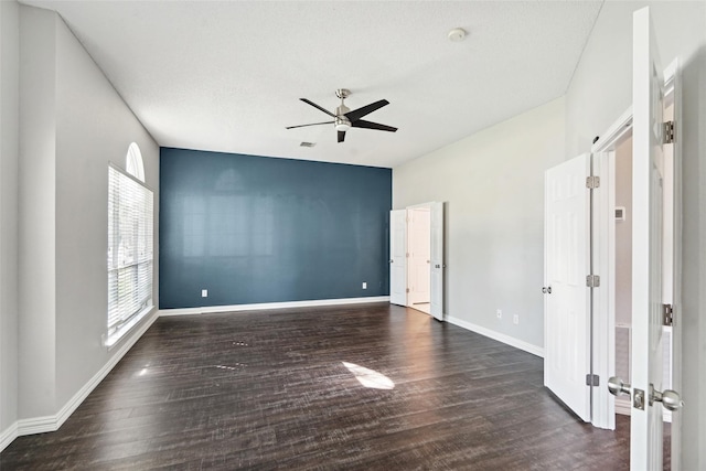 unfurnished room featuring a healthy amount of sunlight, ceiling fan, and dark wood-type flooring