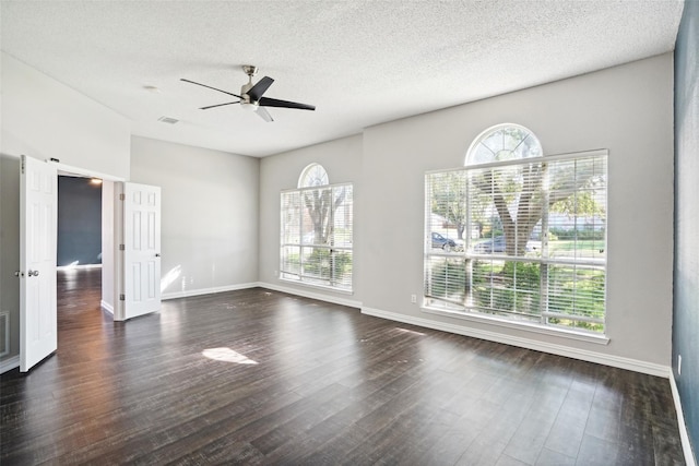 spare room with a textured ceiling, dark hardwood / wood-style flooring, plenty of natural light, and ceiling fan