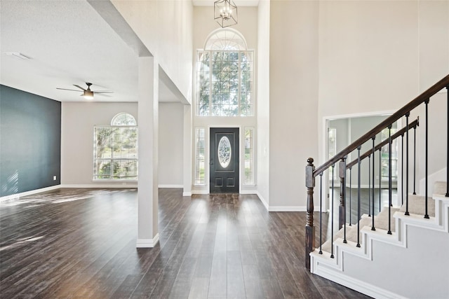 foyer with ceiling fan with notable chandelier, a high ceiling, and dark hardwood / wood-style floors