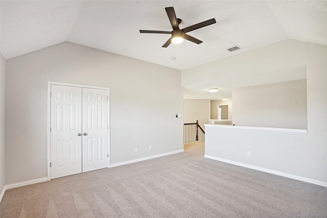 empty room featuring light colored carpet, vaulted ceiling, and ceiling fan