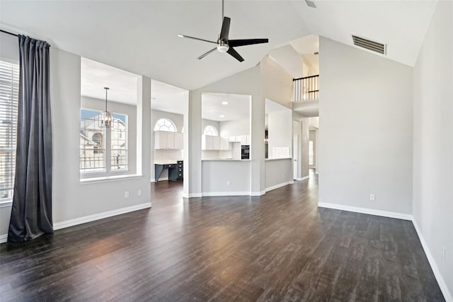 unfurnished living room with ceiling fan with notable chandelier, dark hardwood / wood-style floors, and high vaulted ceiling